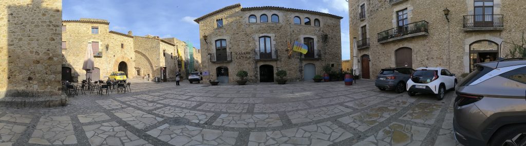 Plaza Mayor à Pals. Su cette place nous voyons la Mairie, quelques boutiques, un bar et l'accès par passage en arcade à la partie haute de Pals.
