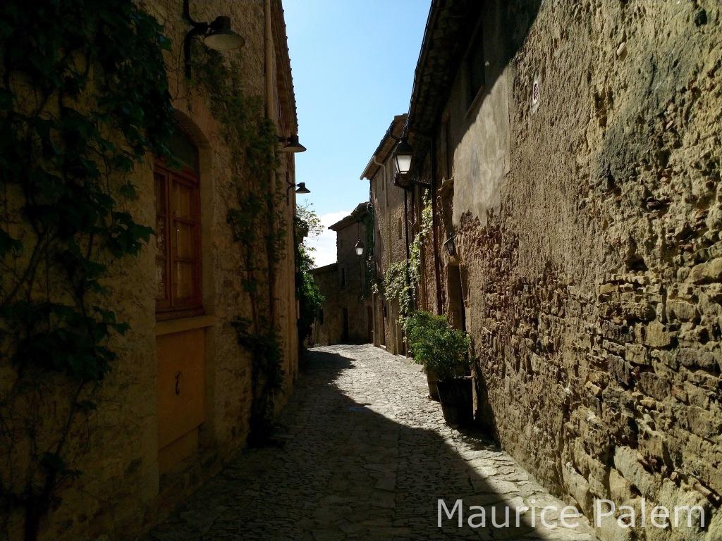 ici une ruelle de Peratallada serpente entre les façades des maison haute, en pierre jaune